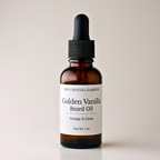 An amber glass dropper bottle of Golden Vanilla Beard Oil by The Crystal Garden, featuring a white label and a black rubber dropper cap, set against a plain light beige background.