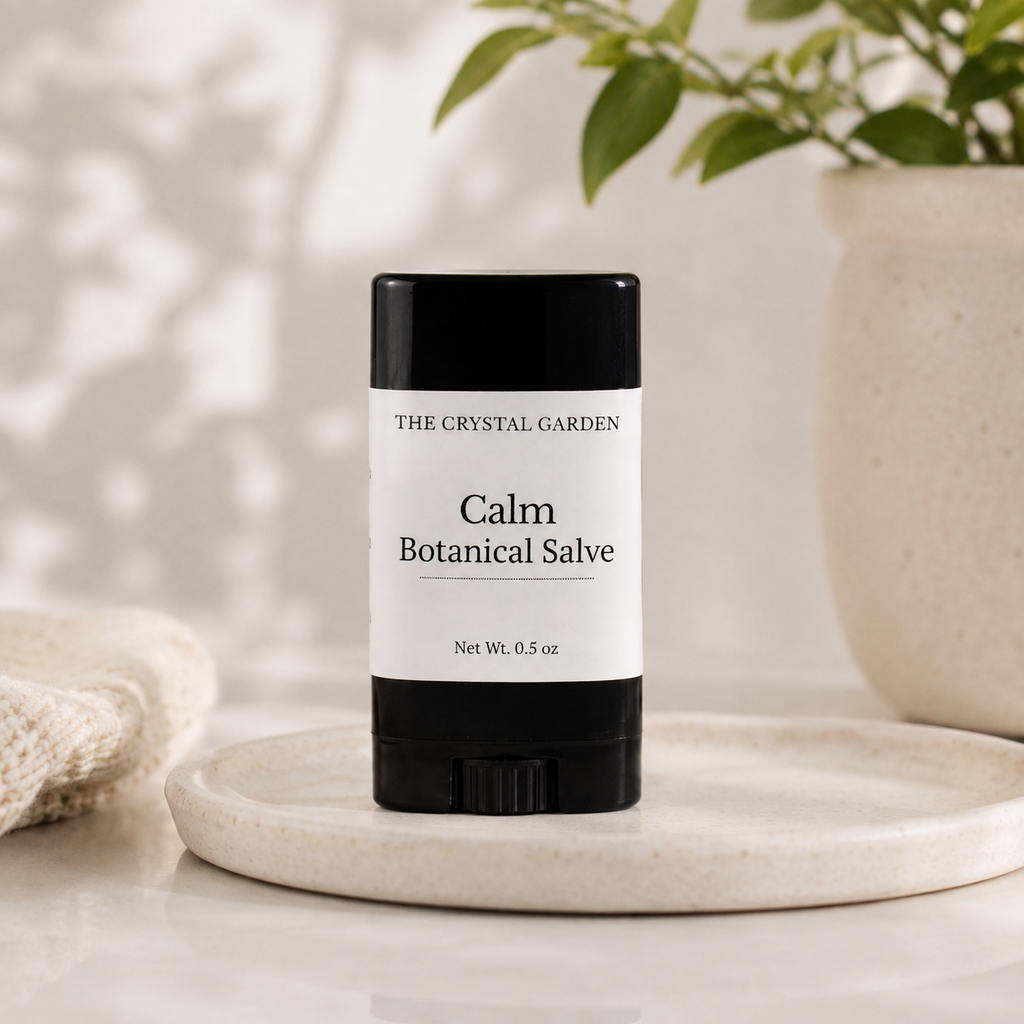 A single stick of 'Calm Botanical Salve' by 'The Crystal Garden' sits on a round marble tray. The product features a black container with a white label.