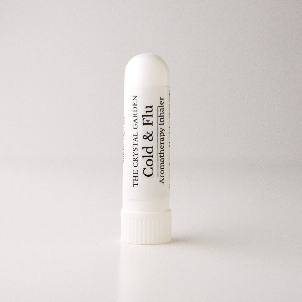 A white plastic cold and flu aromatherapy inhaler tube by The Crystal Garden, standing upright on a light gray background.