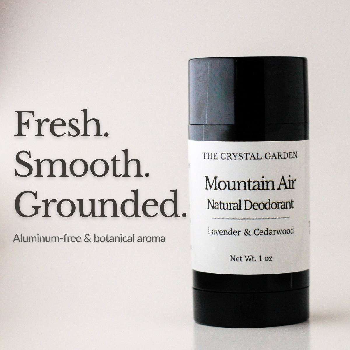 A 1 oz deodorant stick from The Crystal Garden, Mountain Air Natural Deodorant, in a black container with a white label. The image includes text on the left reading 'Fresh. Smooth. Grounded. Aluminum-free and botanical aroma'