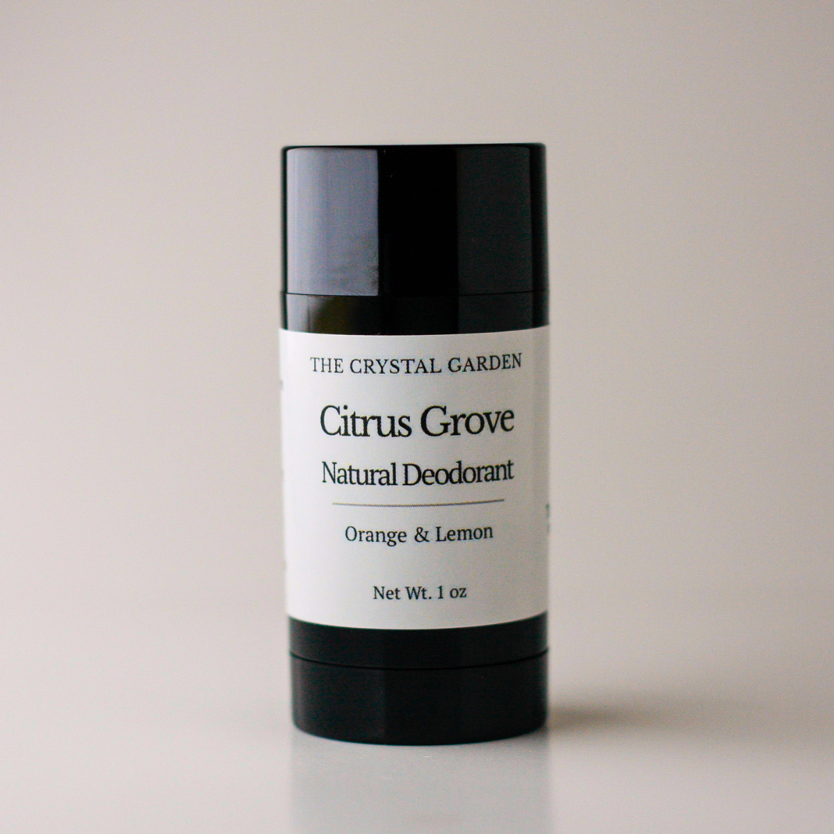 A black plastic stick container of The Crystal Garden Citrus Grove Natural Deodorant with a white paper label, set against a plain light gray background.