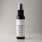 A 2 oz amber glass spray bottle of The Crystal Garden Deodorizing Spray in Pure Citrus scent, featuring a white label and black spray nozzle, set against a neutral gray background.