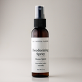 A 2 oz amber glass spray bottle of The Crystal Garden Deodorizing Spray with a white label and black spray nozzle, set against a neutral light gray background.