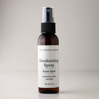 A 2 oz amber glass spray bottle of The Crystal Garden Deodorizing Spray with a white label and black spray nozzle, set against a neutral light gray background.
