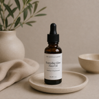 A 1 oz amber glass dropper bottle of 'The Crystal Garden' Everyday Glow Face Oil, styled on a ceramic dish with a neutral beige background and soft-focus props.