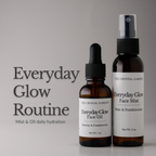 Two amber skincare bottles from The Crystal Garden on a light gray background. The left bottle is a dropper bottle of Everyday Glow Face Oil, and the right bottle is a spray bottle of Everyday Glow Face Mist.