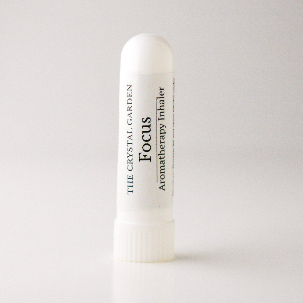 A white cylindrical aromatherapy inhaler tube with a ribbed cap, featuring a white label with black text that reads 'THE CRYSTAL GARDEN Focus Aromatherapy Inhaler'.