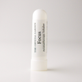 A white cylindrical aromatherapy inhaler tube with a ribbed cap, featuring a white label with black text that reads 'THE CRYSTAL GARDEN Focus Aromatherapy Inhaler'.