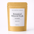 A single-use stand-up pouch of The Crystal Garden Botanical Mineral Soak in Grounded scent, made of natural kraft paper with a white label.