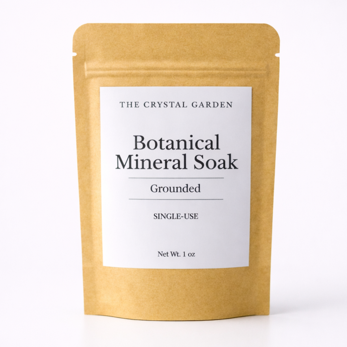 A single-use stand-up pouch of The Crystal Garden Botanical Mineral Soak in Grounded scent, made of natural kraft paper with a white label.