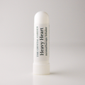A white cylindrical aromatherapy inhaler tube standing upright on a light gray background. The label reads 'THE CRYSTAL GARDEN Heavy Heart Aromatherapy Inhaler' in black text.
