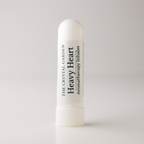 A white cylindrical aromatherapy inhaler tube standing upright on a light gray background. The label reads 'THE CRYSTAL GARDEN Heavy Heart Aromatherapy Inhaler' in black text.
