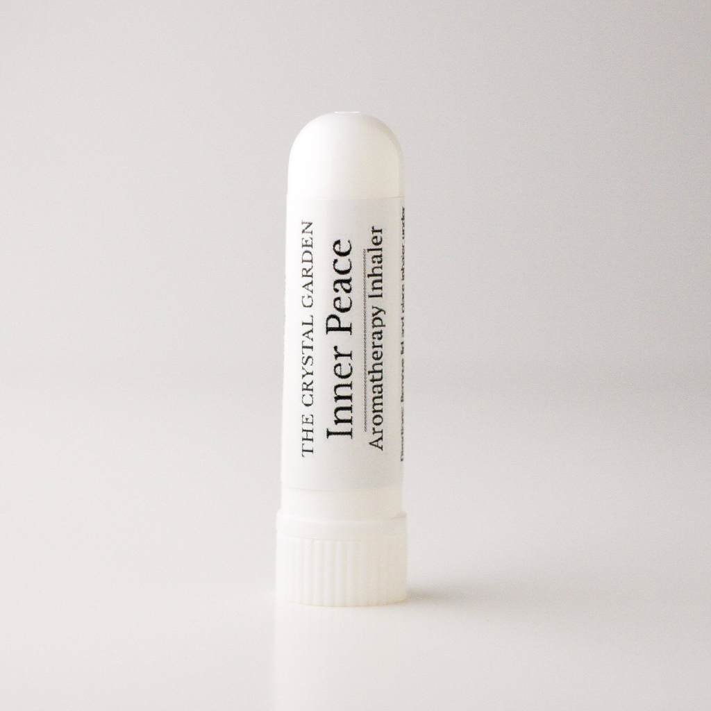 A white plastic aromatherapy inhaler tube standing upright on a light gray background. The label reads 'THE CRYSTAL GARDEN' and 'Inner Peace Aromatherapy Inhaler'.