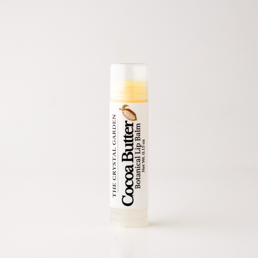 A single tube of The Crystal Garden Cocoa Butter Botanical Lip Balm on a clean white background.