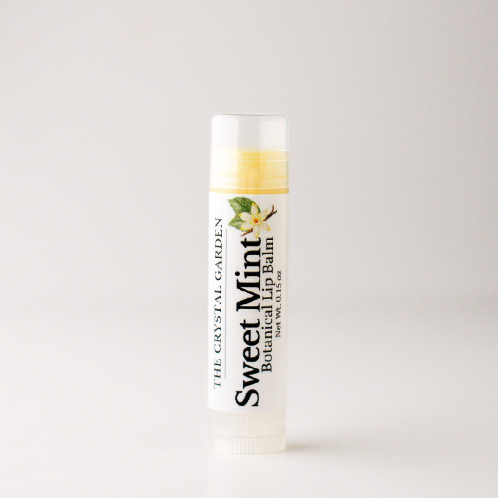 A tube of The Crystal Garden Sweet Mint Botanical Lip Balm with a white cap and a white label featuring black text and a small green leaf graphic, set against a plain light gray background.