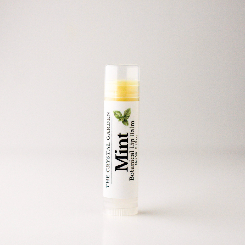 A single tube of mint botanical lip balm from The Crystal Garden, standing upright on a clean white surface against a light gray background.