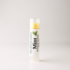 A single tube of mint botanical lip balm from The Crystal Garden, standing upright on a clean white surface against a light gray background.