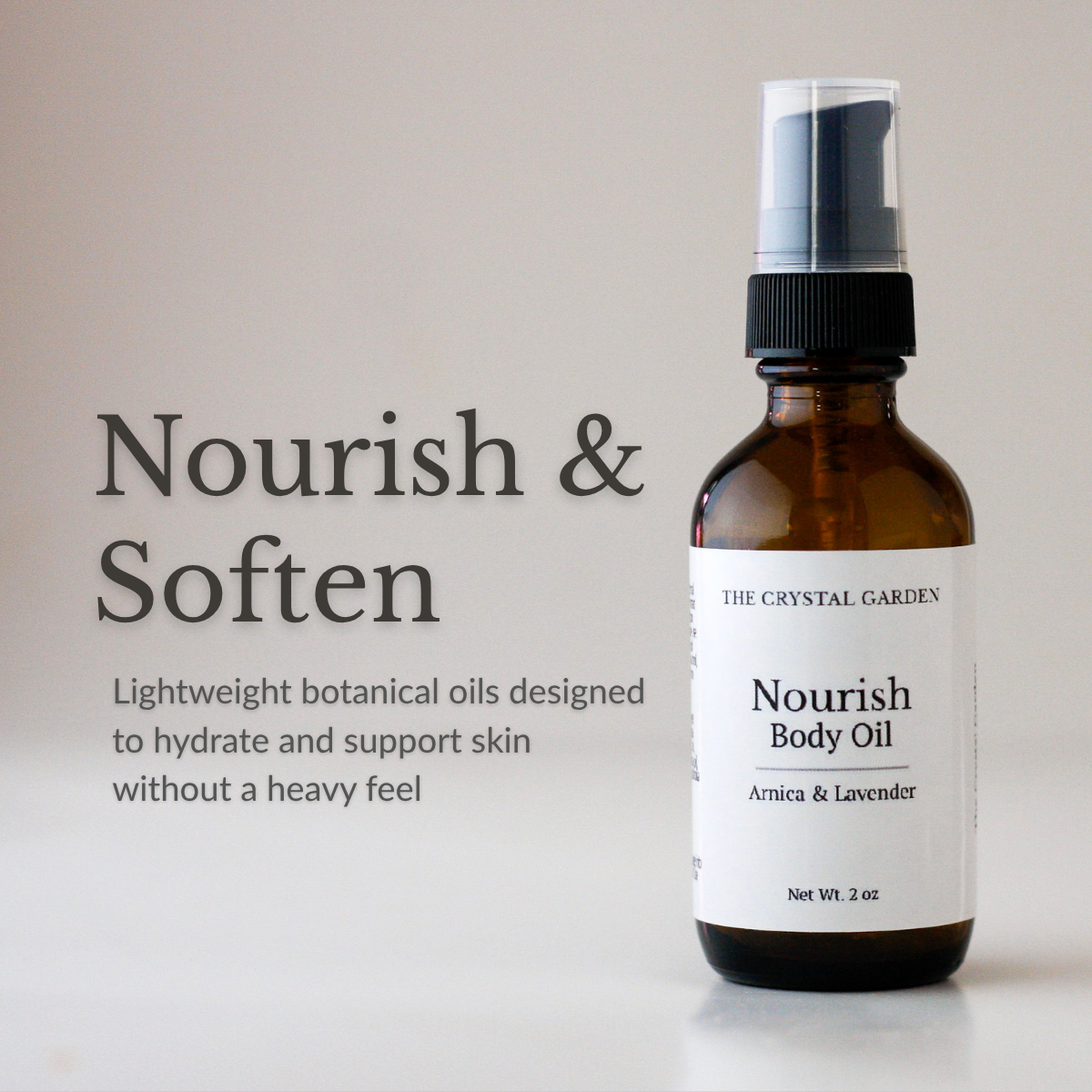 Amber glass spray bottle of The Crystal Garden Nourish Body Oil with a white label and black spray top, shown beside text reading 'Nourish & Soften' on a light neutral background.