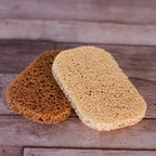 Two natural Soap Savers , one light tan and one medium brown, displayed on a rustic wooden surface.