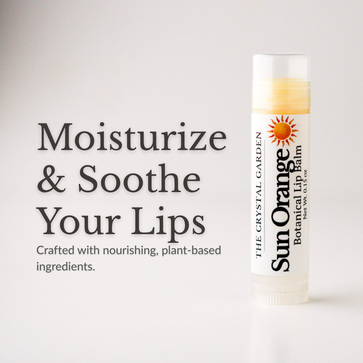 A tube of Sun Orange Botanical Lip Balm by The Crystal Garden is shown on the right against a light gray background, with large marketing text on the left reading 'Moisturize & Soothe Your Lips.' No person, animal, or real environment is present, so this is Product/Packaging rather than Lifestyle.