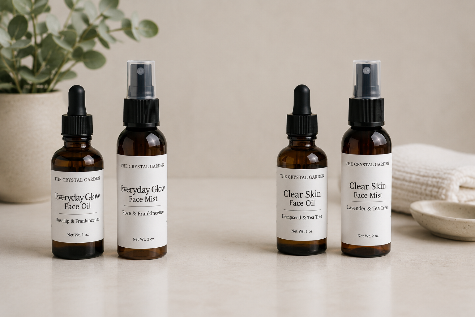 Four amber skincare bottles from The Crystal Garden are lined up on a light beige surface. The bottles include Everyday Glow Face Oil, Everyday Glow Face Mist, Clear Skin Face Oil, and Clear Skin Face Mist, with white labels and black droppers/sprayers.