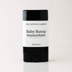 A single stick of baby cream or balm with a black container and a white label reading 'THE CRYSTAL GARDEN Baby Bump Botanical Butter' on a clean white background.