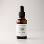 An amber glass dropper bottle of The Crystal Garden Healing Nail Oil on a light gray background.