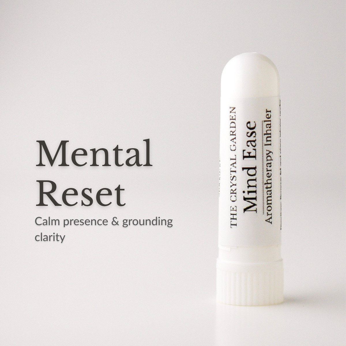 A white cylindrical aromatherapy inhaler tube labeled 'The Crystal Garden Mind Ease' stands on a light gray background beside large text reading 'Mental Reset' and smaller descriptive copy.