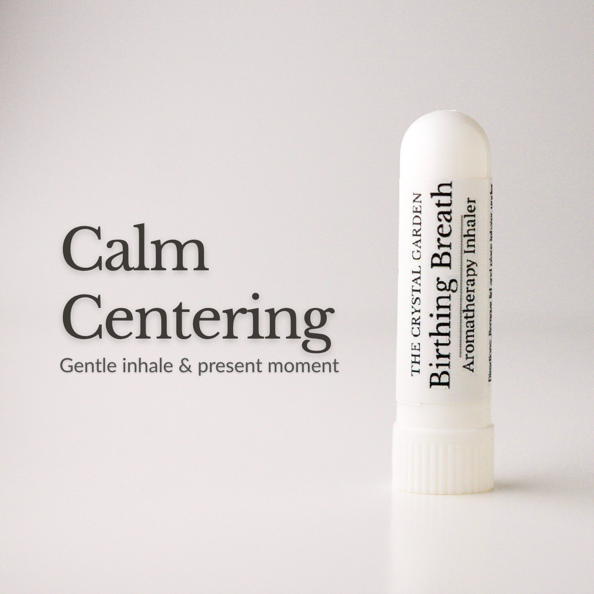 A white cylindrical aromatherapy inhaler tube stands on a light gray background next to the text 'Calm Centering' and 'Gentle inhale & present moment.' The tube is labeled 'The Crystal Garden Birthing Breath Aromatherapy inhaler.