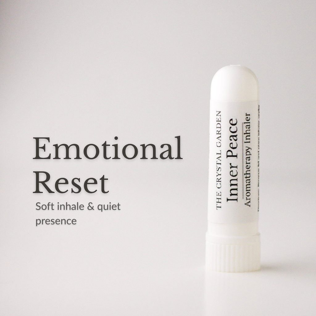 A white cylindrical aromatherapy inhaler bottle stands on a light gray background next to black text that reads 'Emotional Reset' and 'Soft inhale & quiet presence.' The bottle label shows 'The Crystal Garden' and 'Inner Peace.
