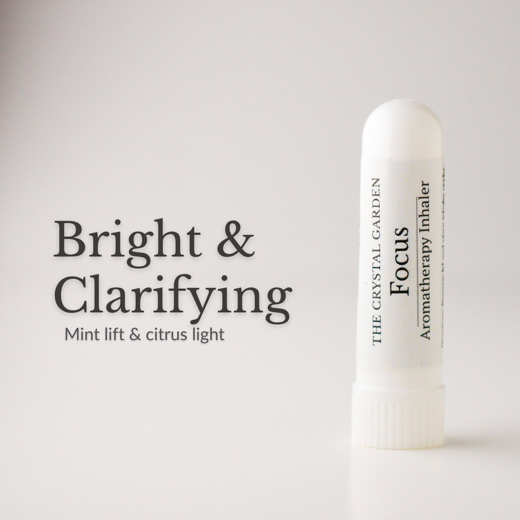 A white cylindrical aromatherapy inhaler tube labeled 'The Crystal Garden Focus Aromatherapy Inhaler' stands on a light gray background next to text reading 'Bright & Clarifying' and 'Mint lift & citrus light'.