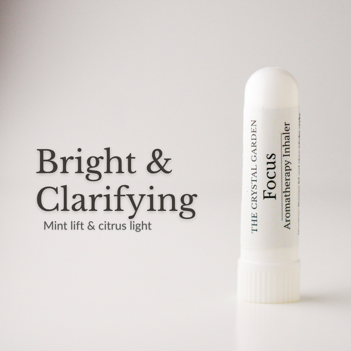 A white cylindrical aromatherapy inhaler tube labeled 'The Crystal Garden Focus Aromatherapy Inhaler' stands on a light gray background next to text reading 'Bright & Clarifying' and 'Mint lift & citrus light'.