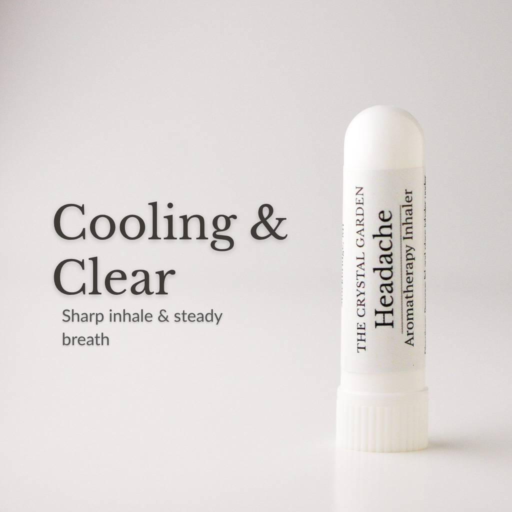 A white cylindrical aromatherapy inhaler tube stands on a light gray background next to black text that reads 'Cooling & Clear' and 'Sharp inhale & steady breath.' The tube is labeled 'THE CRYSTAL GARDEN Headache Aromatherapy Inhaler.