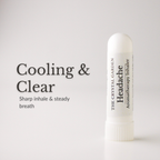 A white cylindrical aromatherapy inhaler tube stands on a light gray background next to black text that reads 'Cooling & Clear' and 'Sharp inhale & steady breath.' The tube is labeled 'THE CRYSTAL GARDEN Headache Aromatherapy Inhaler.
