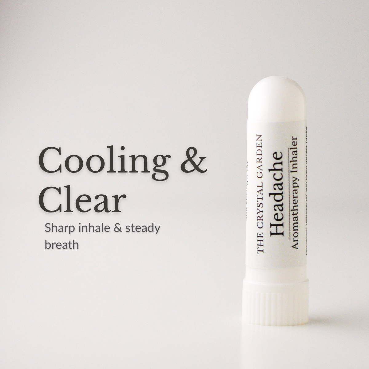 A white cylindrical aromatherapy inhaler tube stands on a light gray background next to black text that reads 'Cooling & Clear' and 'Sharp inhale & steady breath.' The tube is labeled 'THE CRYSTAL GARDEN Headache Aromatherapy Inhaler.