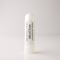 A white cylindrical aromatherapy inhaler tube standing upright on a light gray background. The label reads 'THE CRYSTAL GARDEN Mind Ease Aromatherapy Inhaler' in black text.
