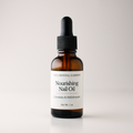 An amber glass dropper bottle of The Crystal Garden Nourishing Nail Oil with a white label and black dropper cap, set against a clean light gray background.