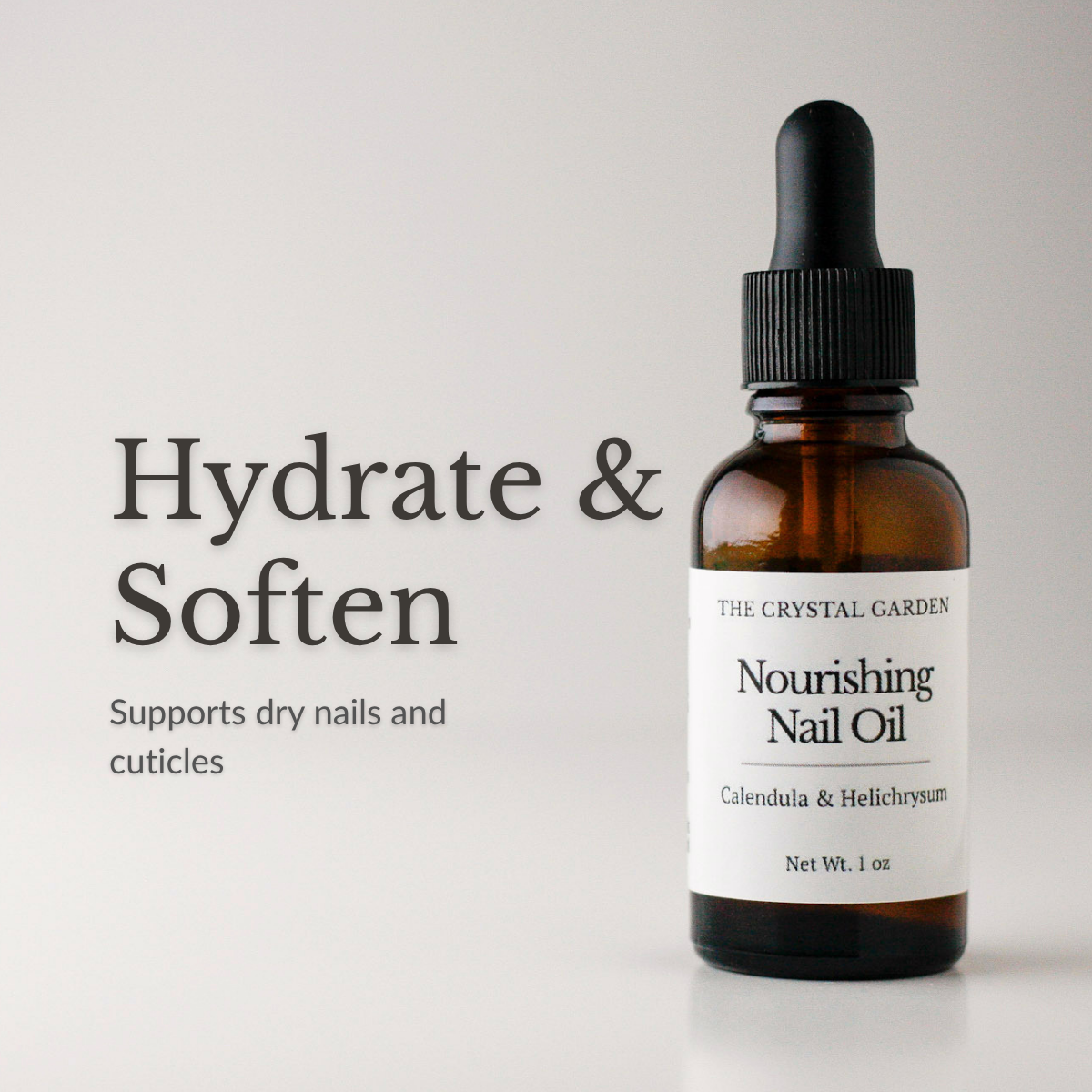 Amber glass dropper bottle of The Crystal Garden Nourishing Nail Oil with a white label and black dropper cap, shown on a light gray background with the text 'Hydrate & Soften' and 'Supports dry nails and cuticles'.