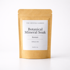 A single-use stand-up pouch of The Crystal Garden Botanical Mineral Soak in the Restore scent, made of natural kraft paper with a white label, shot against a clean white background.