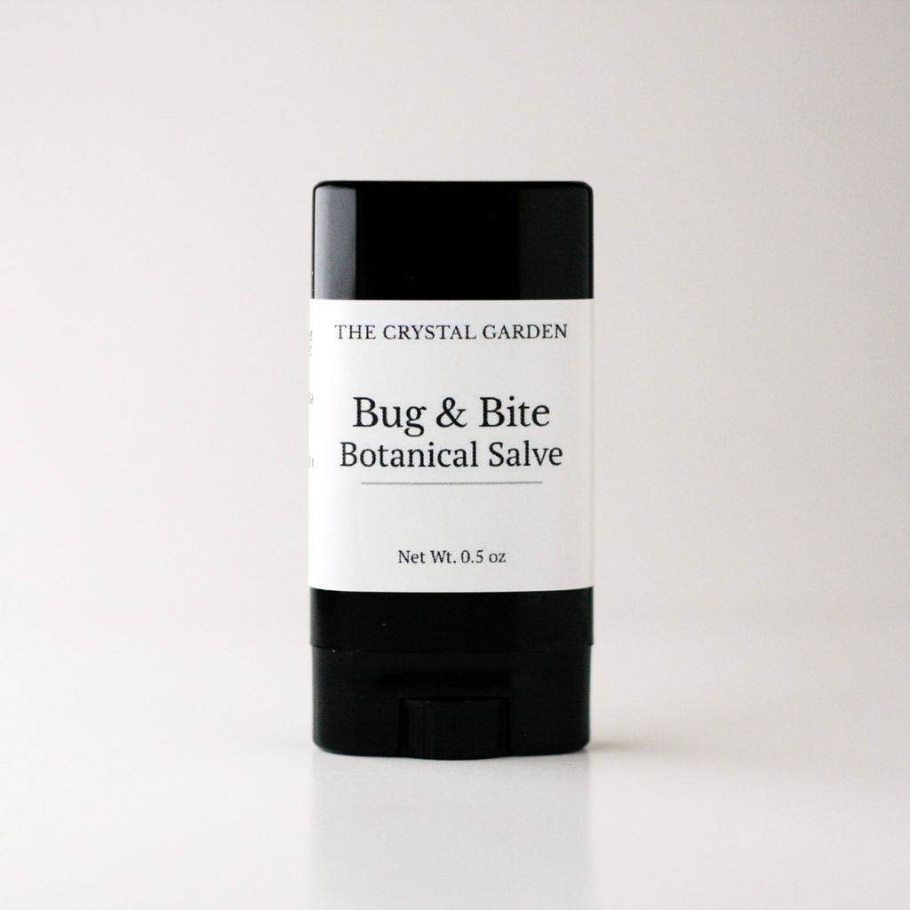 A single stick of 'Bug & Bite Botanical Salve' by 'The Crystal Garden' in a black and white container, centered on a light gray background.