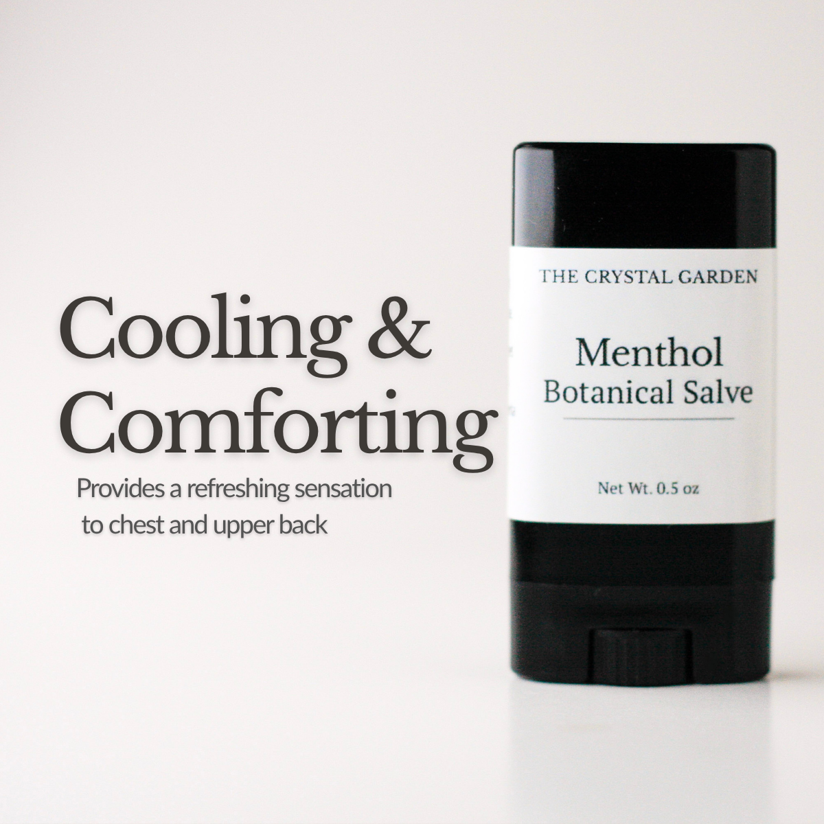A black and white stick of The Crystal Garden Menthol Botanical Salve stands on a white surface against a white background, with text on the left reading 'Cooling & Comforting'.