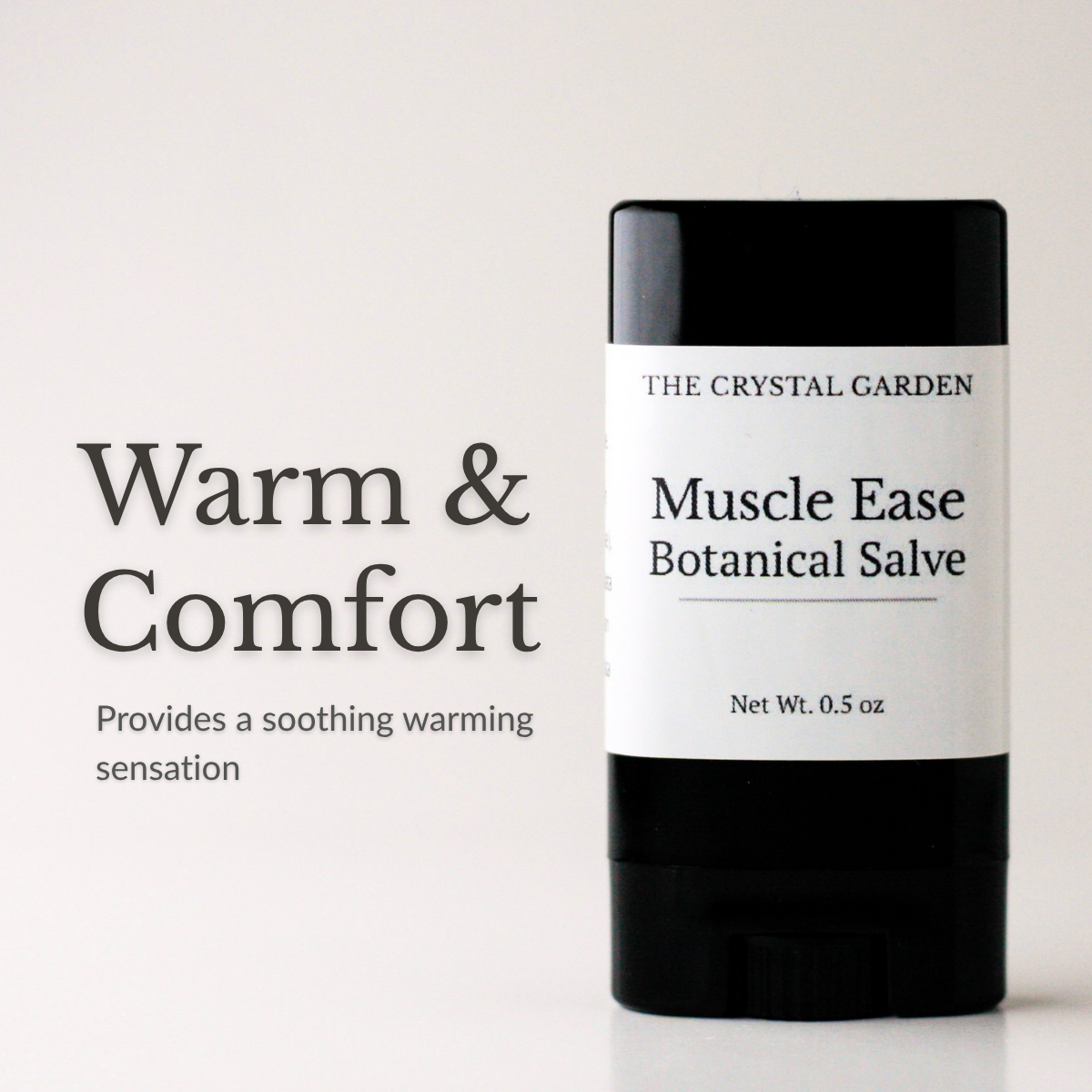 A black and white stick of The Crystal Garden Muscle Ease Botanical Salve stands on a white surface against a white background, with text on the left reading 'Warm & Comfort' and 'Provides a soothing warming sensation.'.