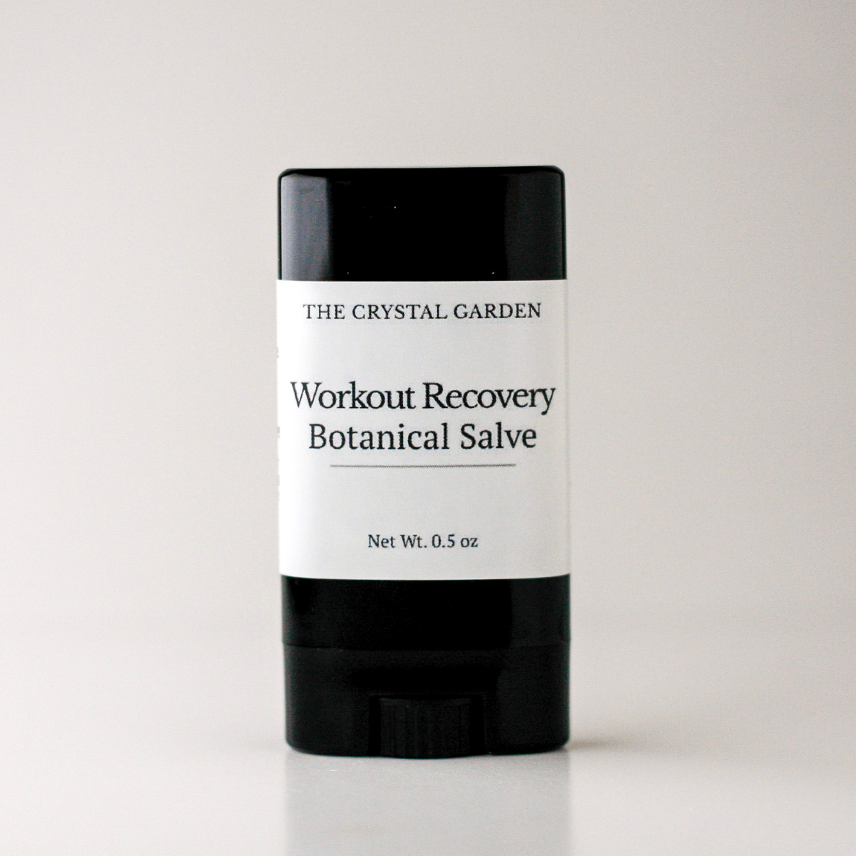 A black and white stick container of The Crystal Garden Workout Recovery Botanical Salve, centered on a light gray background.