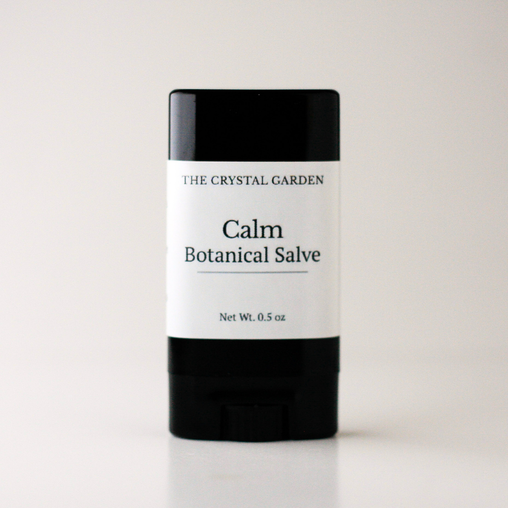 A single stick of salve from The Crystal Garden, specifically 'Calm Botanical Salve', in a black container with a white label, set against a plain light background.