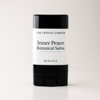 A single stick of salve from The Crystal Garden, specifically Inner Peace Botanical Salve, in a black plastic container with a white paper label, set against a plain light background.