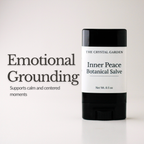 A black and white deodorant-style stick labeled 'The Crystal Garden Inner Peace Botanical Salve' stands on a light neutral background beside large text reading 'Emotional Grounding' and smaller supporting text.